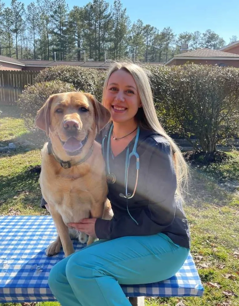 Morgan Bischoff sitting on an outside table with a dog.